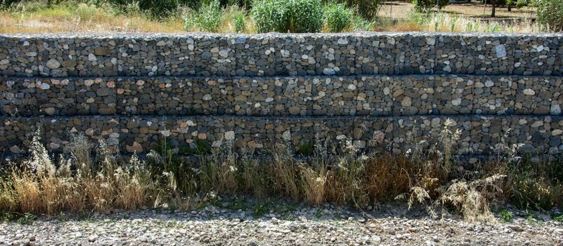 A tiered stone retaining wall with grasses along the base